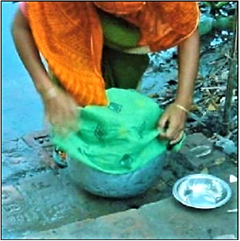 UNKNOWN (n.y): A woman uses a sari cloth to strain water